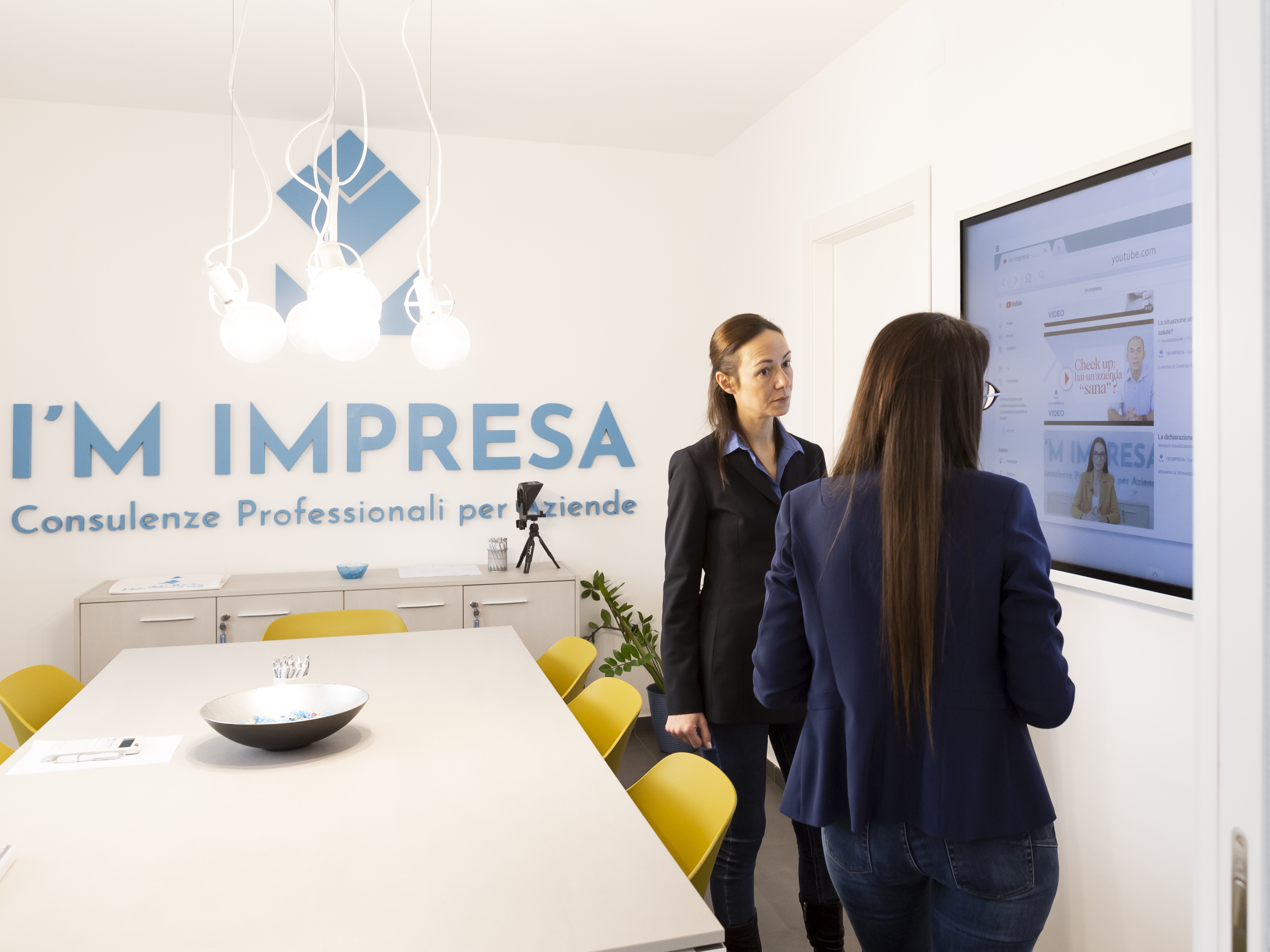 Logo aziendale “I’m Impresa” con simbolo geometrico astratto in tonalità blu, sopra il nome del brand.