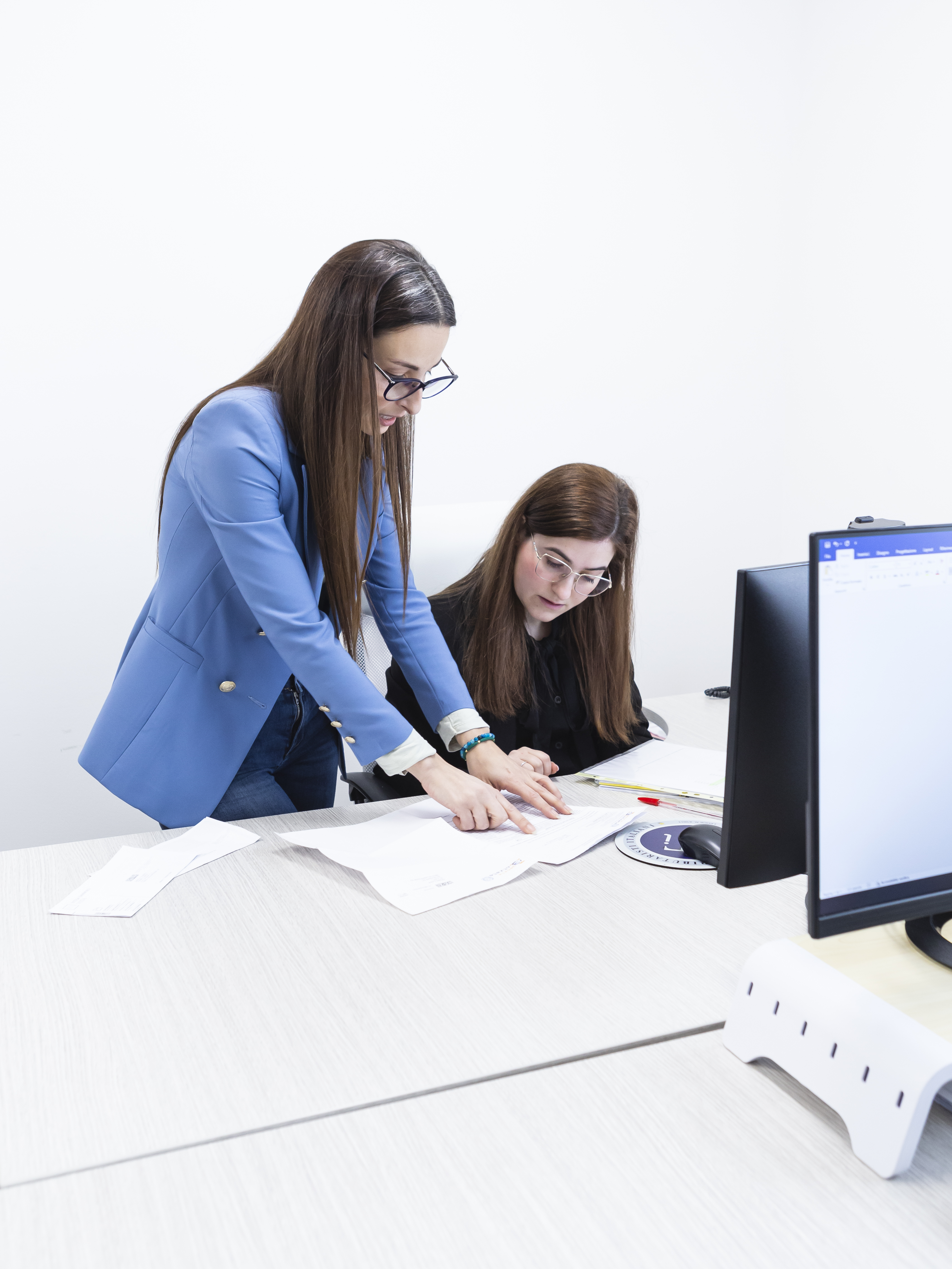 Due professioniste osservano e analizzano contenuti su uno schermo digitale interattivo in ufficio.