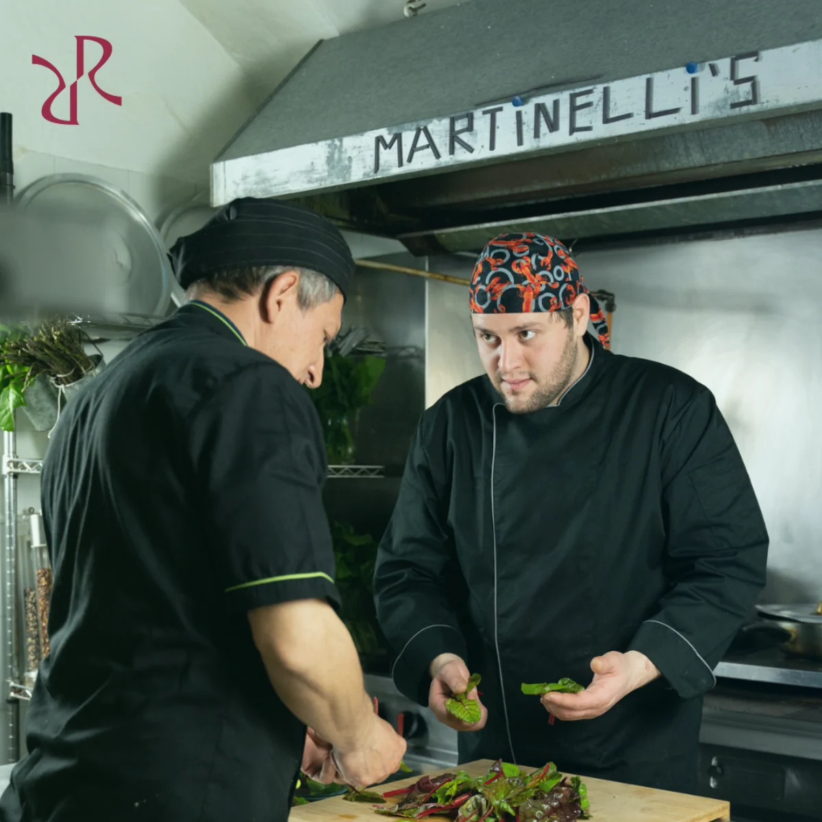 Lo chef Roberto di Martinelli’s e un membro del suo team preparano ingredienti freschi in cucina, simbolo dell’eccellenza culinaria e dell’innovazione digitale del ristorante di Cagliari.